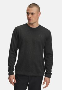 Schwarzes Sweatshirt mit langen Ärmeln aus strukturiertem Stoff, Rundhalsausschnitt und gerippten Bündchen. Verfügt über ein dezentes Logo auf der Brust.