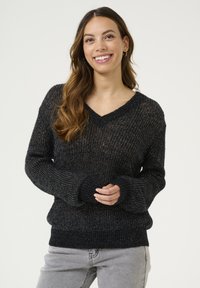 Svart stickad tröja med V-ringning, långa ärmar och ribbade muddar. Har en strukturerad design med metalltrådsdetaljer.