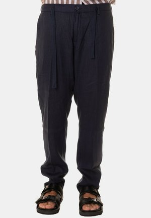 Pantaloni in lino blu navy con vita regolabile, vestibilità affusolata e due tasche laterali, abbinati a sandali neri con cinturini regolabili.