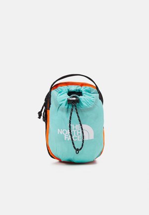 Kompakt turkis snorepose med sort snor, orange sider, et sort håndtag og hvidt "The North Face"-logo foran.