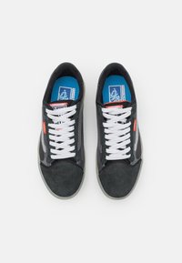 Czarne zamszowe i siateczkowe sneakersy z białymi sznurówkami, szarym logo na boku oraz niebieską wkładką z nadrukiem. Płaska gumowa podeszwa.