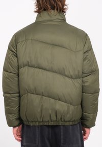Olijf groene gewatteerde jas met een hoge kraag, voorzien van diagonale quiltpatronen, elastische zoom en een gladde, glanzende stoftextuur.