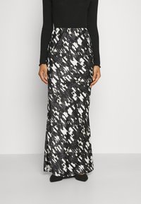 Jupe longue et fluide en tissu léger, avec un motif abstrait noir et blanc. Taille élastique et silhouette élégante.