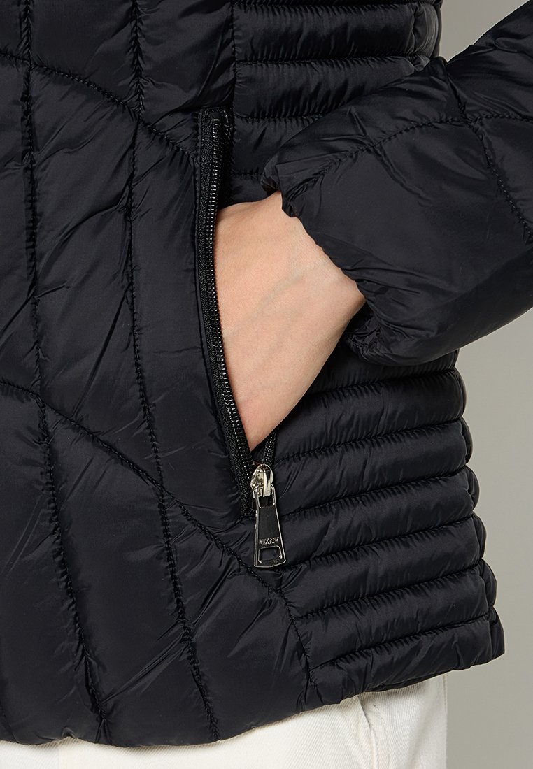 Chaqueta acolchada negra aislante con un patrón de acolchado, que cuenta con un bolsillo con cremallera y puños acanalados. Textura suave con un acabado brillante.