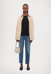 Beige leren jasje, zwarte t-shirt, lichtblauwe straight-leg jeans, zwarte ballerina's en een kleine beige handtas met een gebogen ontwerp.