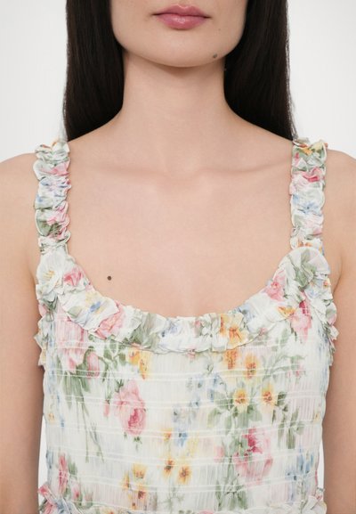 Bloemrijke jurk met geplooid wit materiaal, versierd met meerkleurige bloemen, ruches op de schouderbanden en een vierkante halslijn.