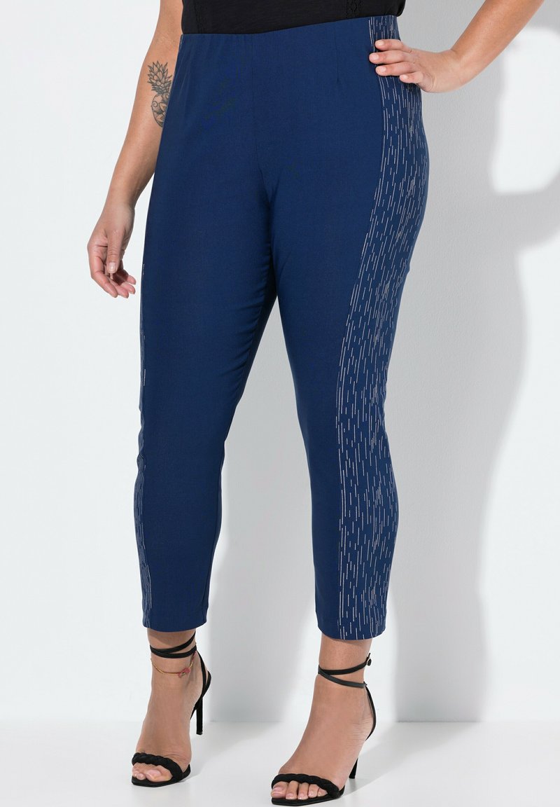 Pantaloni blu navy alla caviglia con una trama liscia, caratterizzati da un motivo verticale metallico lungo il lato e una vita elastica.