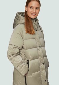 Lichtbeige pufferjack met capuchon, voorzien van een gequiltde textuur, drukknoopsluiting en zijzakken met zwarte trekkoorden.