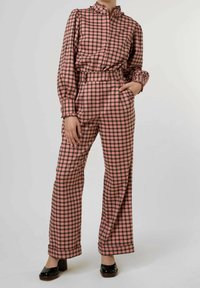 Set di blusa e pantaloni a quadretti in rosa e nero. La blusa presenta un colletto arricciato; i pantaloni sono a gamba larga con un fit rilassato.