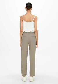 Lekką, kremową bluzkę na ramiączkach z cienkimi paskami połączoną z wysokimi spodniami o prostym kroju w stonowanym odcieniu oliwkowym. Prosty design.