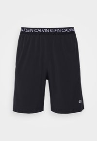 Svarta träningsshorts med en slät yta, elastisk midjeresår som har "CALVIN KLEIN" tryckt och en liten vit logotyp på nedre högra sidan.