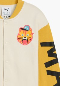 Tofarvet sweatshirt i creme og gul med et tigeransigt grafik og en blå kasket. Sort tekst på ærmet skaber kontrast. Blødt stof.