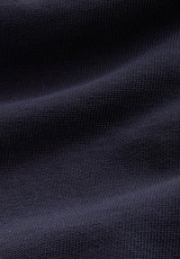 Primo piano di tessuto a maglia blu navy scuro che mostra una trama dettagliata e un motivo a coste fine in morbide pieghe.