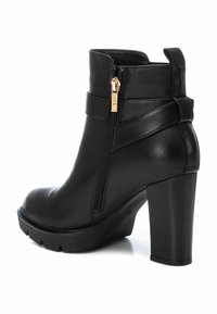 Botín negro de tobillo hecho de cuero sintético, con un alto tacón de bloque, cremallera lateral con herrajes dorados y una suela texturizada para mayor tracción.