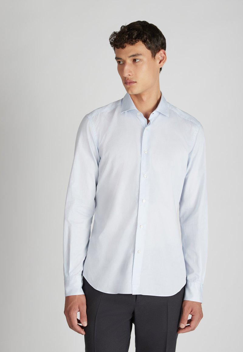 Camicia azzurra a maniche lunghe, con bottoni sul davanti, colletto classico, realizzata in tessuto morbido con una texture liscia, dotata di un orlo curvo e vestibilità regolare.
