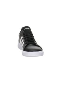 Czarne syntetyczne sneakersy z białą gumową podeszwą, z trzema białymi paskami po boku i czarnymi sznurowadłami. Okrągły czubek, siateczkowy język.