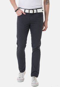 Marineblaue, strukturierte Hose mit schlanker Passform und weißem Gürtel. Verfügt über Taschen vorne und wird mit weißen Sneakers getragen.