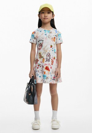 Ein kurzärmliges, knielanges Kleid mit hellem Hintergrund, das mit bunten Tier- und Lebensmittelillustrationen verziert ist. Begleitet von einer schwarzen Tasche.