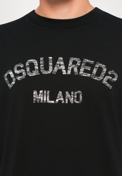 T-shirt nera a girocollo con testo bianco scolorito "DSQUARED2" che si arca sopra "MILANO" sul petto.