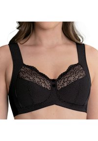 Schwarzer BH aus gepunktetem Textil, mit transparentem Spitzenoberteil und breiten Trägern, das in der Mitte mit einem dekorativen Knopfdetail versehen ist.
