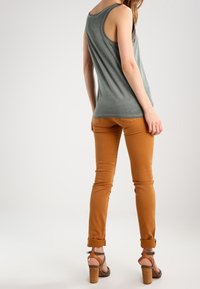 Gray tank top, fitted design; paired with rust-colored slim-fit pants; tan heeled sandals with ankle straps and wooden block heels.