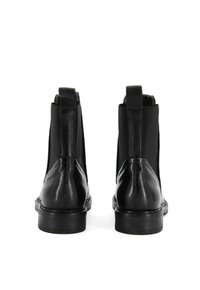 Bottines Chelsea en cuir noir avec panneaux latéraux élastiques, une finition lisse et un bout arrondi. Comprend des languettes pour un enfilage facile.