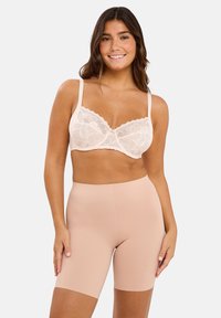 Bralette en dentelle avec un motif floral en beige clair, associée à un short gainant lisse et ajusté couleur nude, de longueur mi-cuisse.
