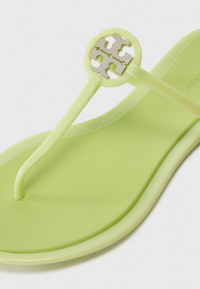 Sandală flip-flop verde cu o talpă din plastic neted și curele asortate. Prezintă un accent metallic circular cu un model de logo.