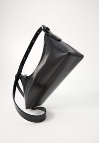 Borsa a tracolla in pelle nera con forma triangolare, strap regolabile e texture liscia. Presenta un branding minimale sul lato.
