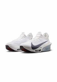 White athletic shoes with a textured mesh upper and a grey Nike swoosh. Features a thick midsole and a black rubber outsole with red accents.