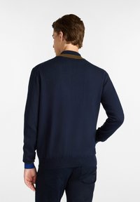 Jersey de punto azul marino con cuello y ribetes en marrón en contraste, mangas largas, puños y dobladillo acanalados, textura suave.