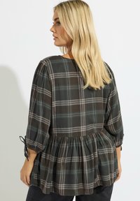 Blusa de cuadros oscuros con escote redondo, mangas tres cuartos con detalles de lazo y cintura fruncida para una silueta peplum.