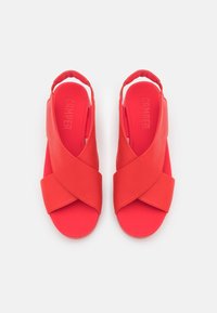 Sandali slingback rossi con design incrociato, realizzati in morbida pelle, con una superficie liscia e una soletta imbottita. Logo impresso sulla soletta.