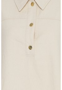 Chemise couleur crème avec col et trois boutons dorés brillants sur le devant.