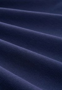 Dunkelblaues, strukturiertes Gewebe mit einem gewebten Muster, das glatte Falten und ein rhythmisches Aussehen zeigt. Geeignet für verschiedene Textilanwendungen.