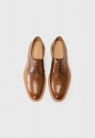 Hnede kožené topánky s hladkým povrchom, zaoblenou špičkou, päťdierkovým dizajnom na šnurovanie a svetlým šitím pozdĺž podrážky.