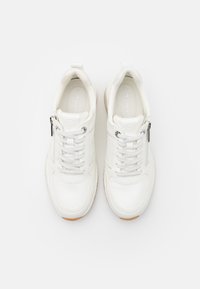 Sneakers bianchi in pelle con pannello laterale testurizzato, lacci e dettaglio con zip. Punta arrotondata e suola in gomma con un accento beige.