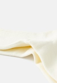 Bomullsblandade strumpor i mjuk krämfärg med ribbad textur; har en slät tåsöm och en elastisk mudd för komfort.