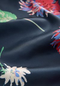 Tissu à motif floral dans un bleu marine foncé, présentant des fleurs rouges et vertes vives. Texture lisse avec un léger éclat.