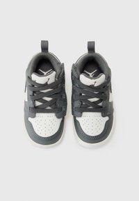Baskets de sport grises et blanches avec une tige en cuir, un bout perforé, des lacets et une sangle. Présente un logo sur la languette et un intérieur doux.