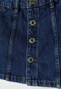Jupe en denim de couleur bleu foncé, avec cinq boutons-pression argentés et des coutures dorées contrastantes, d'une coupe structurée et d'une surface texturée.