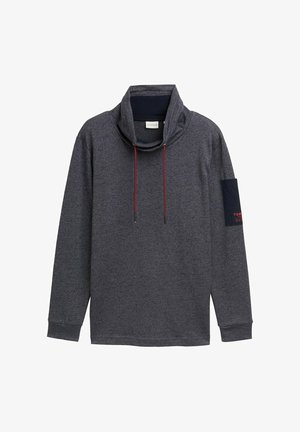 Hedvábný šedý pulovr s dlouhým rukávem a vysokým výstřihem, se stahovacími šňůrkami a námořnickou nášivkou na levém rukávu s červeným textem. Vyrobeno z měkké, texturované tkaniny.