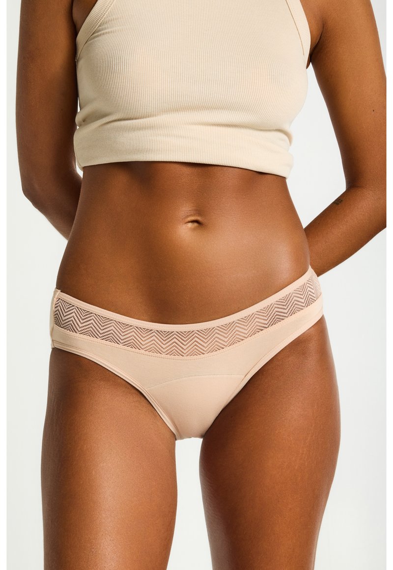 Culotte de bikini beige en tissu lisse avec un motif chevron texturé sur la taille. Présente un design taille basse.