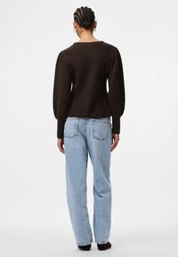 Tumši brūns adīts džemperis ar puff mērvienībām, apvienots ar gaiši ziliem augsta vidukļa džinsiem ar aizmugurējām kabatām un brīvu piegriezumu.