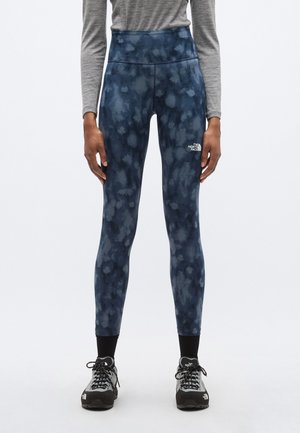 Tumesinise lipsuvärviga kõrge vöökohaga retuusid, millel on vasakul reiel brändilogo ja siledast, venivast kangast.