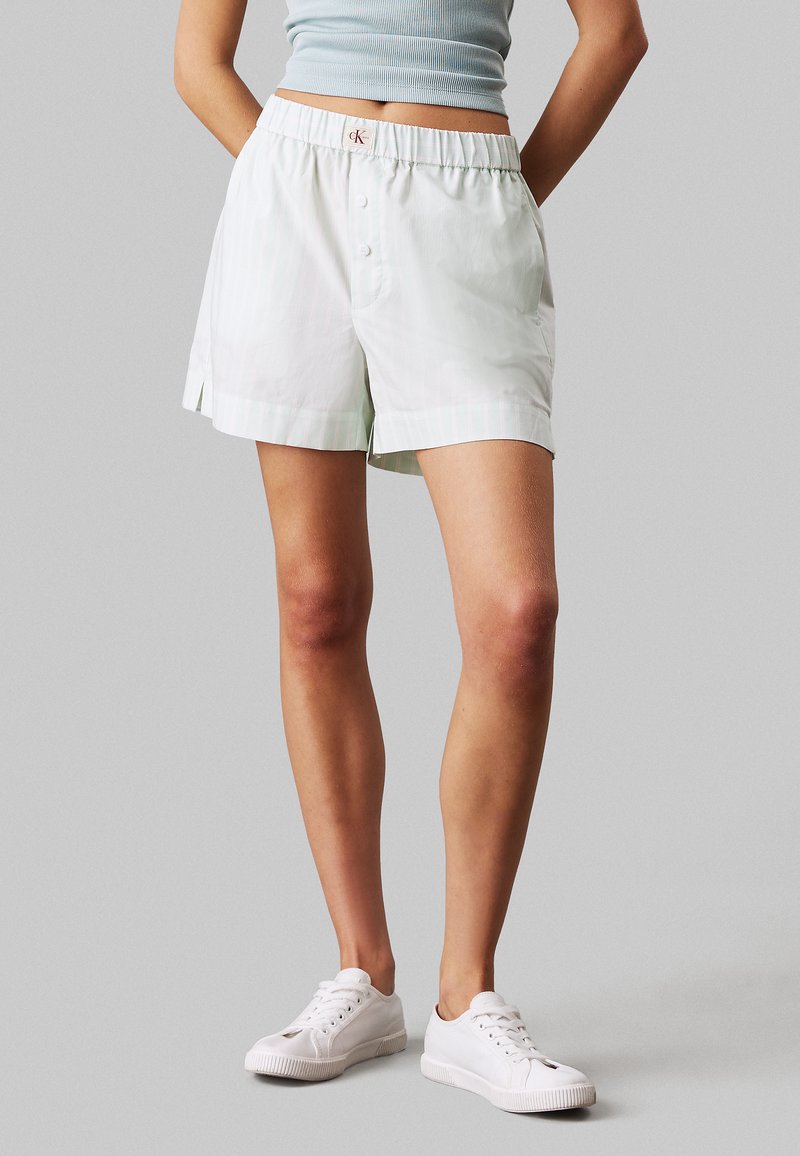 Shorts de rayas verde claro con cintura elástica y detalle de botón. Confeccionados en tejido suave. Presentan aperturas laterales para mayor comodidad.