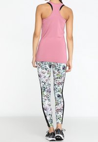 Top sportivo rosa abbinato a leggings con motivo floreale e strisce nere laterali. Design leggero e aderente; adatto per l'esercizio.