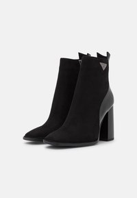 Bottines noires en cuir suédé et en cuir, avec un bout pointu et un talon épais haut. Fermeture éclair sur le côté et détail de logo accentué.