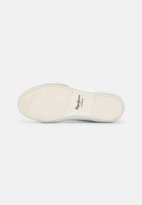 Suola di sneaker bianca con superficie in gomma texturizzata, caratterizzata da un motivo a spina di pesce e un sottile logo del marchio in nero. Bordo liscio.