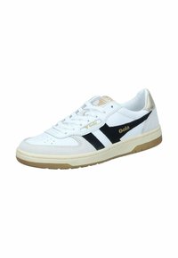 Sneaker bianca con strisce nere, materiale in suede e pelle, punta rotonda, suola piatta, dettagli del logo dorati, suola in gomma leggera color beige contrastante.